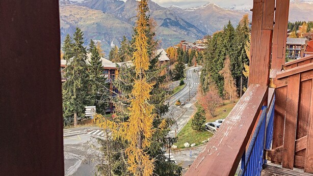 Vista de montanha de uma janela com uma estrada, edifícios e árvores.