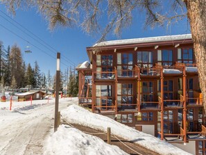 A multi-story wooden building with balconies, surrounded by snow and trees.