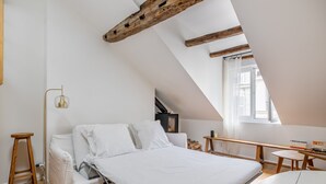 Une chambre de style loft moderne, avec un lit, un bureau et une fenêtre.