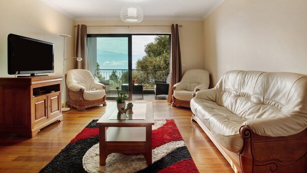 A living room with a TV, two sofas, a coffee table, and a balcony with a view. - Apartment Costa Avila 2 with Sea View, Balconies & Wi-Fi (Caniço)