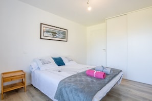 Une chambre à coucher avec un lit, une table de chevet, un tableau encadré au mur et une armoire.