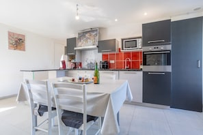 Une cuisine moderne équipée d’une table à manger, de chaises, d’un four à micro-ondes, d’un four et d’un réfrigérateur.