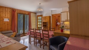 A cozy room with a sofa, dining table, chairs, and a kitchen area with cabinets and a sink. - Apartment 'Le petit chez soi' with Mountain View, Terrace & Wi-Fi (Châtel)