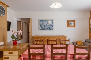 Un coin repas avec une table et des chaises en bois, une horloge et une carte accrochée au mur.