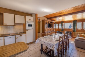 A kitchen with wooden cabinets, a dining table set for four, and a living area with a sofa.