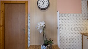 A room with a wooden door, a wall clock, a potted orchid, and a patterned wall. - Apartment La Rose des Vents N 3 with Mountain View, Balcony & Wi-Fi (Chatel)