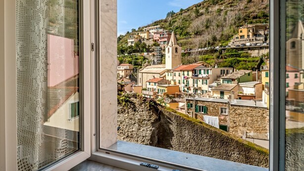 A coastal town with buildings, a church, and a cliffside view. - GuestHost - Cozy 40 sqm studio apartment, accommodating up to 4 people, located on the mezzanine floor of a typical Ligurian home.The property, overlooking the village, is located in Riomaggiore, one of the famous Cinque Terre, about 5 minutes from the t (Riomaggiore)