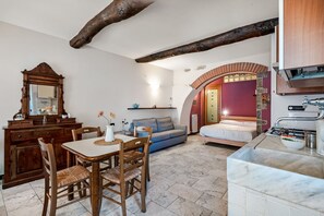 Una habitación acogedora con una mesa de comedor de madera, sillas, un sofá, una cama y una zona de cocina con un fregadero y encimera.