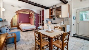 A compact room with a bed, a dining table with chairs, a kitchenette, and a bathroom. - GuestHost - Cozy 40 sqm studio apartment, accommodating up to 4 people, located on the mezzanine floor of a typical Ligurian home.The property, overlooking the village, is located in Riomaggiore, one of the famous Cinque Terre, about 5 minutes from the t (Riomaggiore)