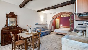 A cozy room with a wooden dining table, chairs, a sofa, a bed, and a kitchen area with a sink and countertop. - GuestHost - Cozy 40 sqm studio apartment, accommodating up to 4 people, located on the mezzanine floor of a typical Ligurian home.The property, overlooking the village, is located in Riomaggiore, one of the famous Cinque Terre, about 5 minutes from the t (Riomaggiore)