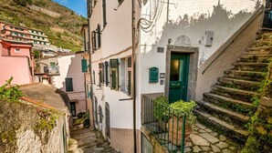 A narrow street with stone steps leading to a building with a green door. - GuestHost - Cozy 40 sqm studio apartment, accommodating up to 4 people, located on the mezzanine floor of a typical Ligurian home.The property, overlooking the village, is located in Riomaggiore, one of the famous Cinque Terre, about 5 minutes from the t (Riomaggiore)