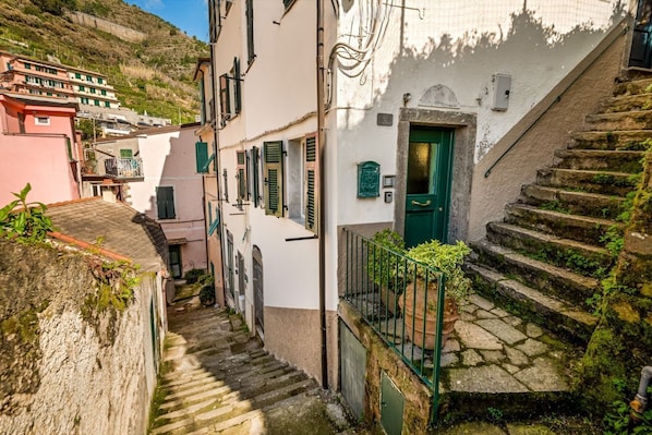 Une rue étroite avec des marches en pierre menant à un bâtiment doté d’une porte verte.