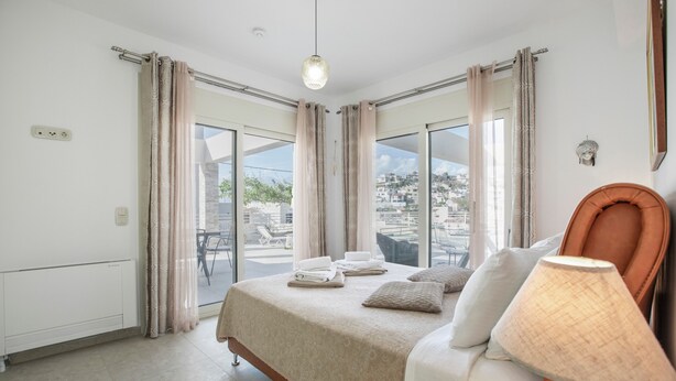 Une chambre d’hôtel avec un lit, une lampe et une vue sur la ville grâce à de grandes fenêtres.