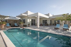 A modern pool area with lounge chairs and a stone structure.