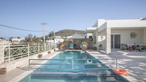 Une piscine équipée d’une barrière de sécurité, un espace patio avec des meubles d’extérieur et une vue sur le quartier environnant.