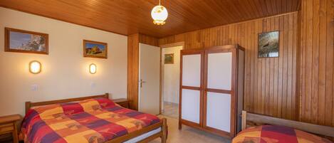 A wooden-paneled room with a bed, bedside tables, and a wardrobe.