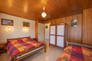 A wooden-paneled room with a bed, bedside tables, and a wardrobe.
