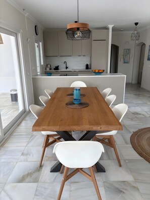 A dining area with a wooden table, white chairs, a blue bowl, and a pendant light.