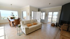 A spacious living area with a sofa, dining table, and chairs, large windows with a view, and a fireplace. - Villa 'With Separate Apartment' near Beach with Pool, Terrace & Wi-Fi (Mijas Costa)