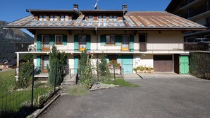 A two-story building with a sloped roof, a balcony, and a garage. - Apartment La rose des vents N 2 with Mountain View, Balcony & Wi-Fi (Chatel)