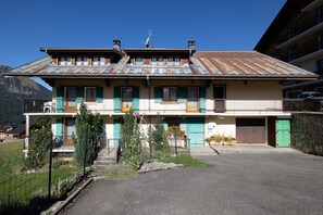 A two-story building with a sloped roof, a balcony, and a garage.