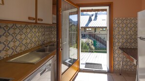 A kitchen with a built-in sink, a wooden countertop, and a sliding glass door leading to a balcony. - Apartment La rose des vents N 2 with Mountain View, Balcony & Wi-Fi (Chatel)