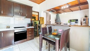 Een moderne keuken met donkere houten kasten, een glazen eettafel en een inbouwoven.