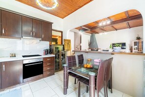 Une cuisine moderne avec des meubles en bois foncé, une table à manger en verre et un four encastré.