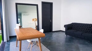 Una habitación con una mesa de madera, un sofá negro y una puerta.