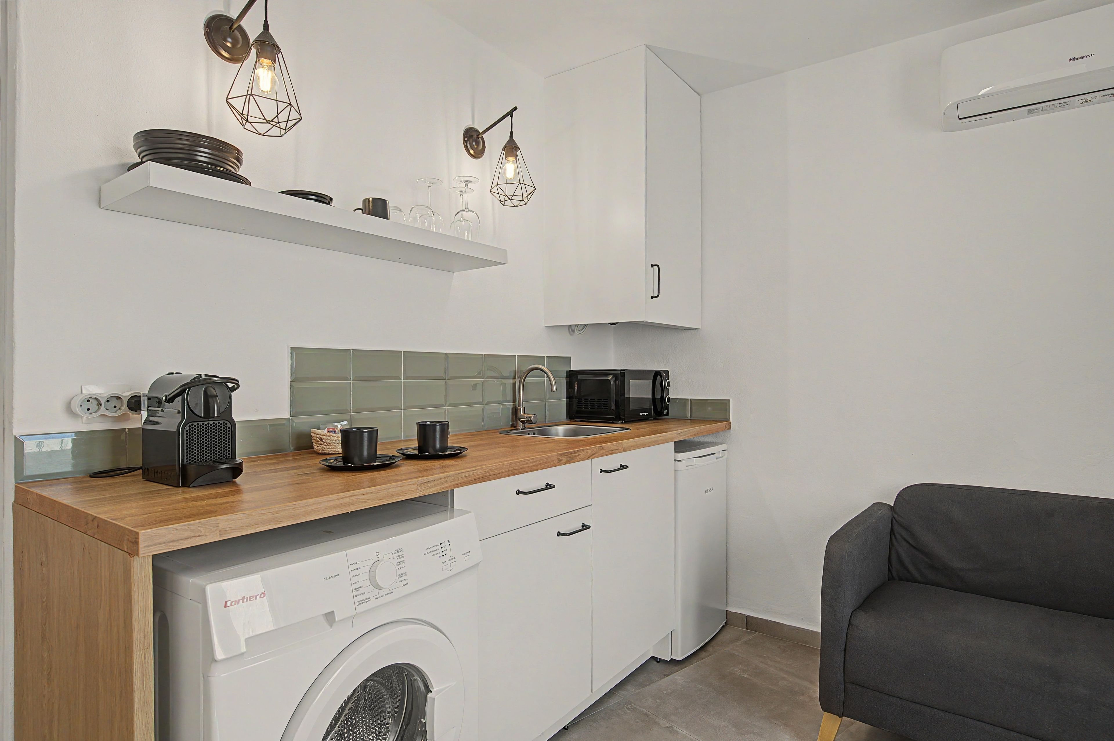 A compact kitchen with a washing machine, a coffee maker, and a microwave.