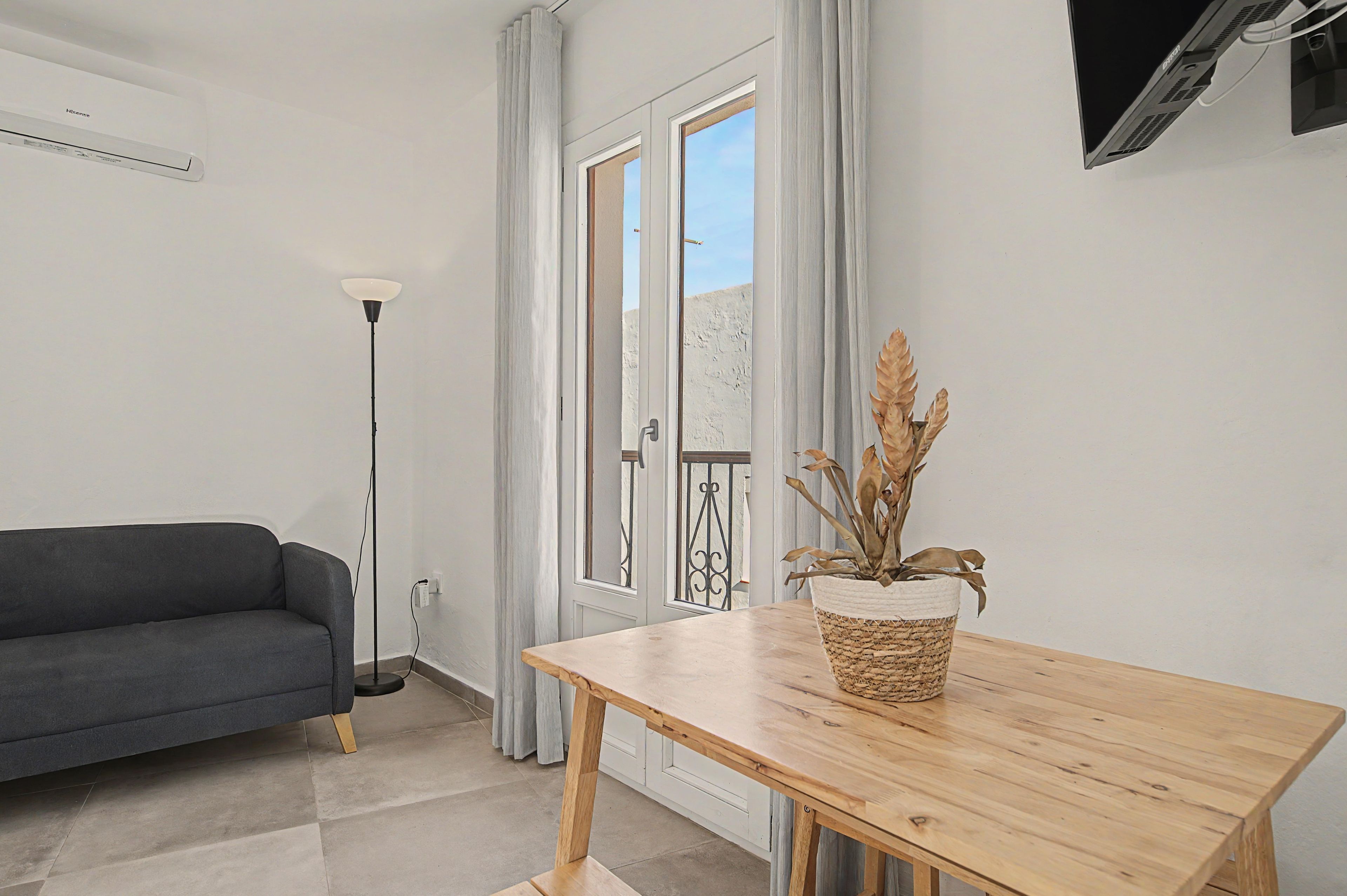 Una sala de estar moderna con un sofá gris, una mesa de madera y una planta en maceta.