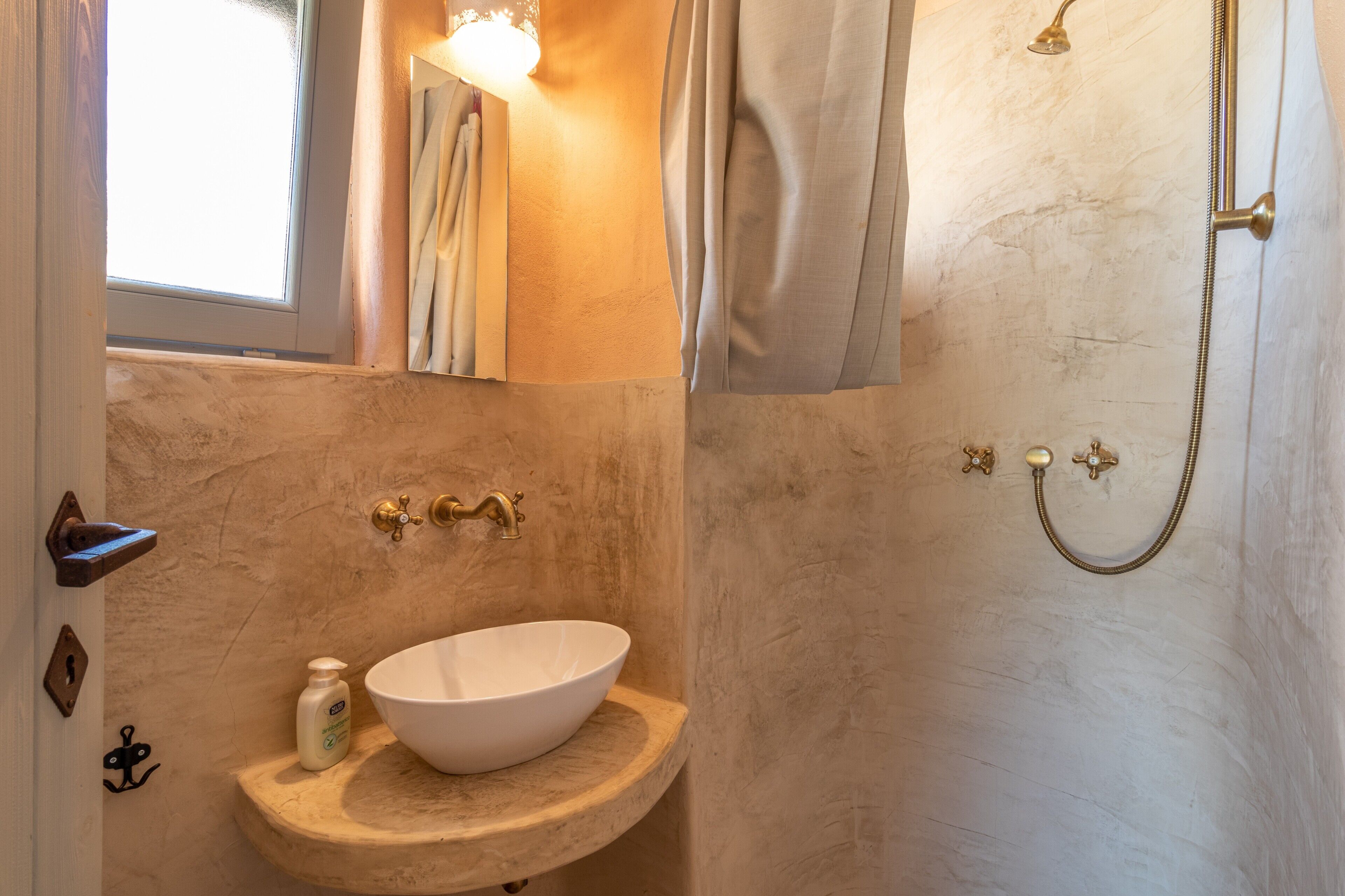 Un baño con lavamanos blanco, ducha y ventana.