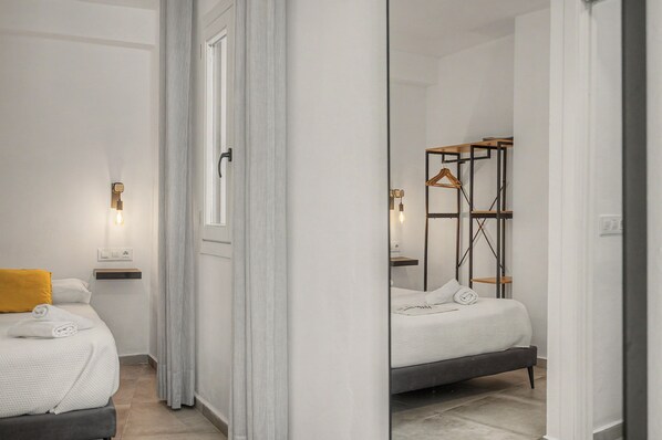 A modern hotel room with a bed, a bedside table, a mirror, and a wardrobe with a hanging rack.