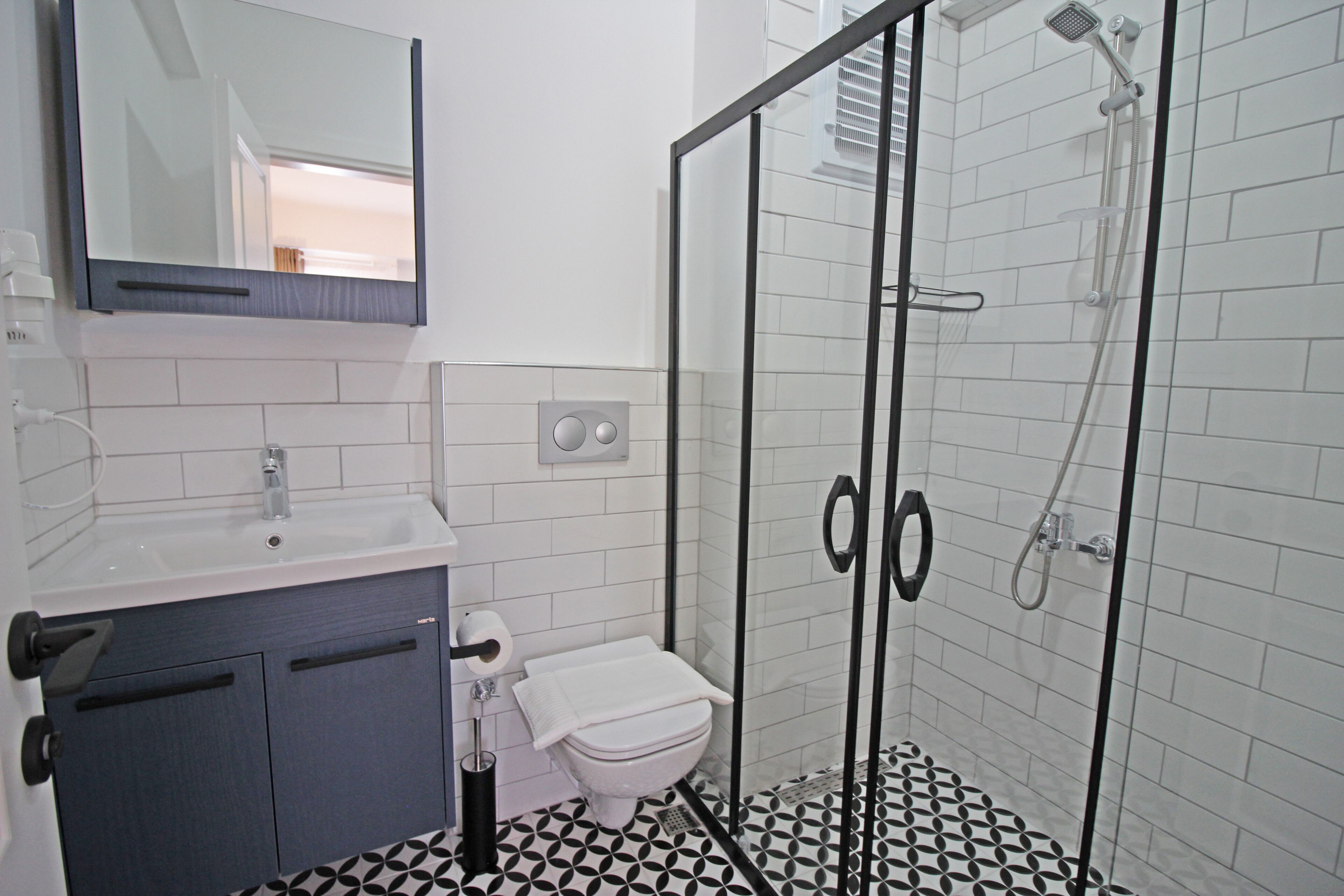A bathroom with a toilet, sink, mirror, and shower.