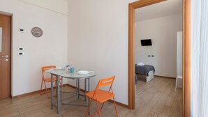 A room with a bed, a TV, a table with chairs, and a door. - Apartment Civico22 - Bilo 3 with Balcony, A/C & Wi-Fi (Peschiera del Garda)
