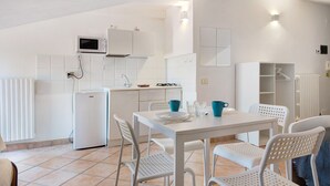 A modern kitchen with white appliances, a dining table with chairs, and a built-in cabinet.