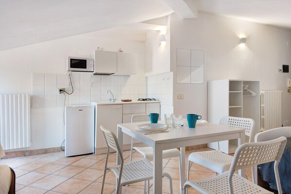 A modern kitchen with white appliances, a dining table with chairs, and a built-in cabinet.