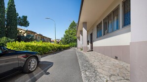A street with a parked car, a building with a stone facade, and a clear sky.