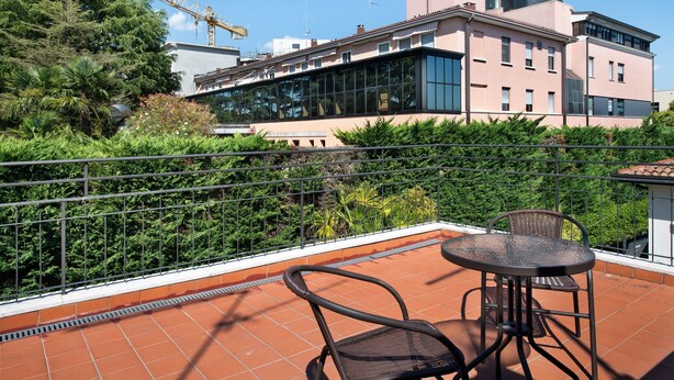 A terrace with a metal railing, a table, and two chairs.