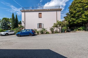 A building with a flat roof, a small window with shutters, and a balcony.
