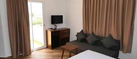 Habitación de hotel con cama, sofá, televisión, escritorio y cafetera.