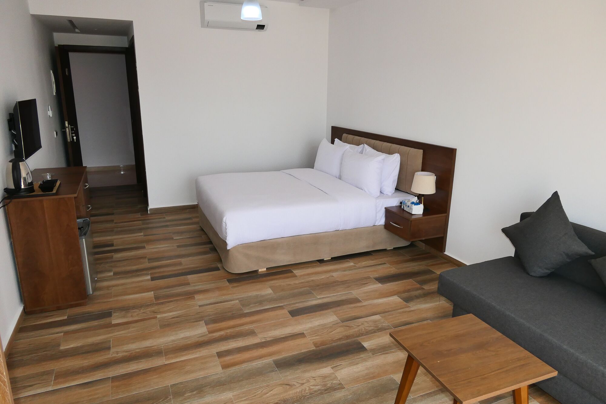 Une chambre d’hôtel comprenant un lit, une table de chevet avec une lampe, un canapé, un bureau en bois et un téléviseur.