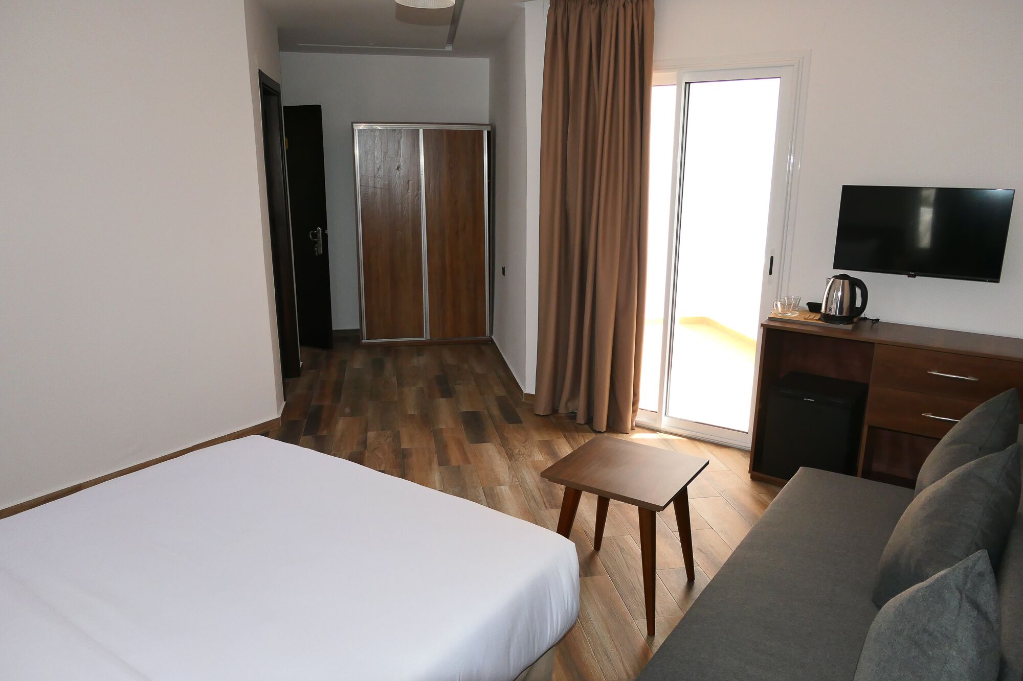 Une chambre d’hôtel équipée d’un lit, d’un canapé, d’une télévision, d’une machine à café et d’une porte coulissante.