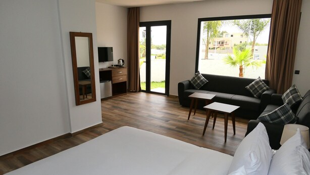 Habitación de hotel con una cama grande, un sofá, una mesita, un televisor y un escritorio con cafetera.