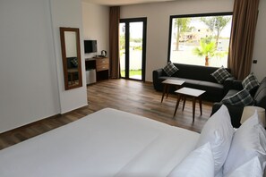 Habitación de hotel con una cama grande, un sofá, una mesita, un televisor y un escritorio con cafetera.