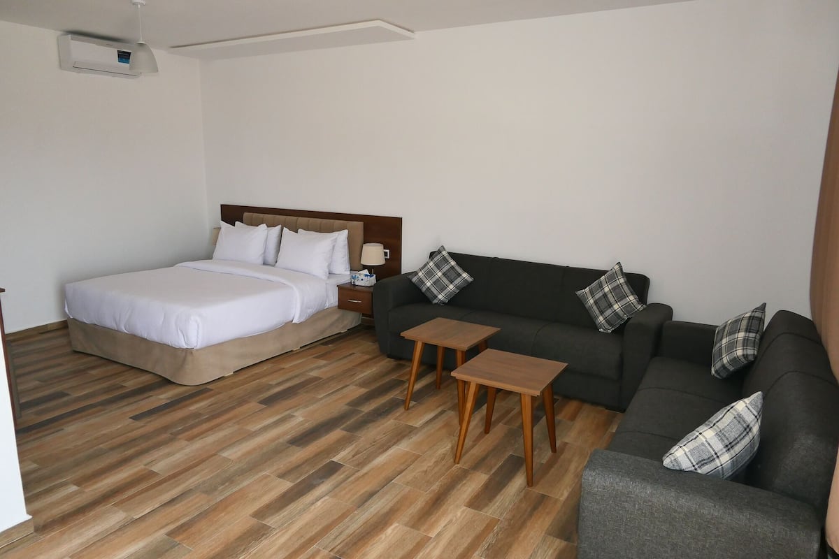 A hotel room with a bed, a sofa, a small table, and a nightstand.