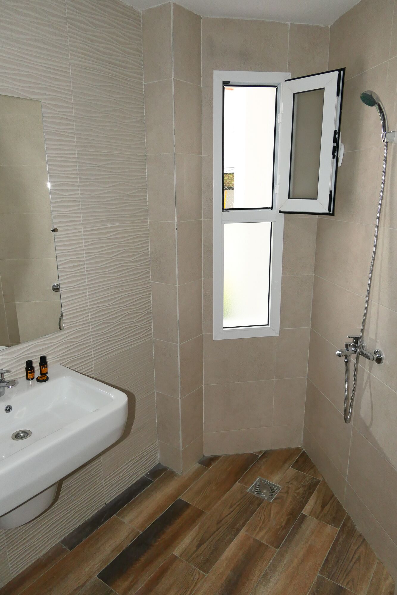 Un baño con lavamanos, espejo, ducha y ventana.