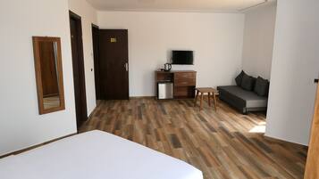 Une chambre d’hôtel comprenant un lit, un bureau avec une télévision, un canapé et une kitchenette.