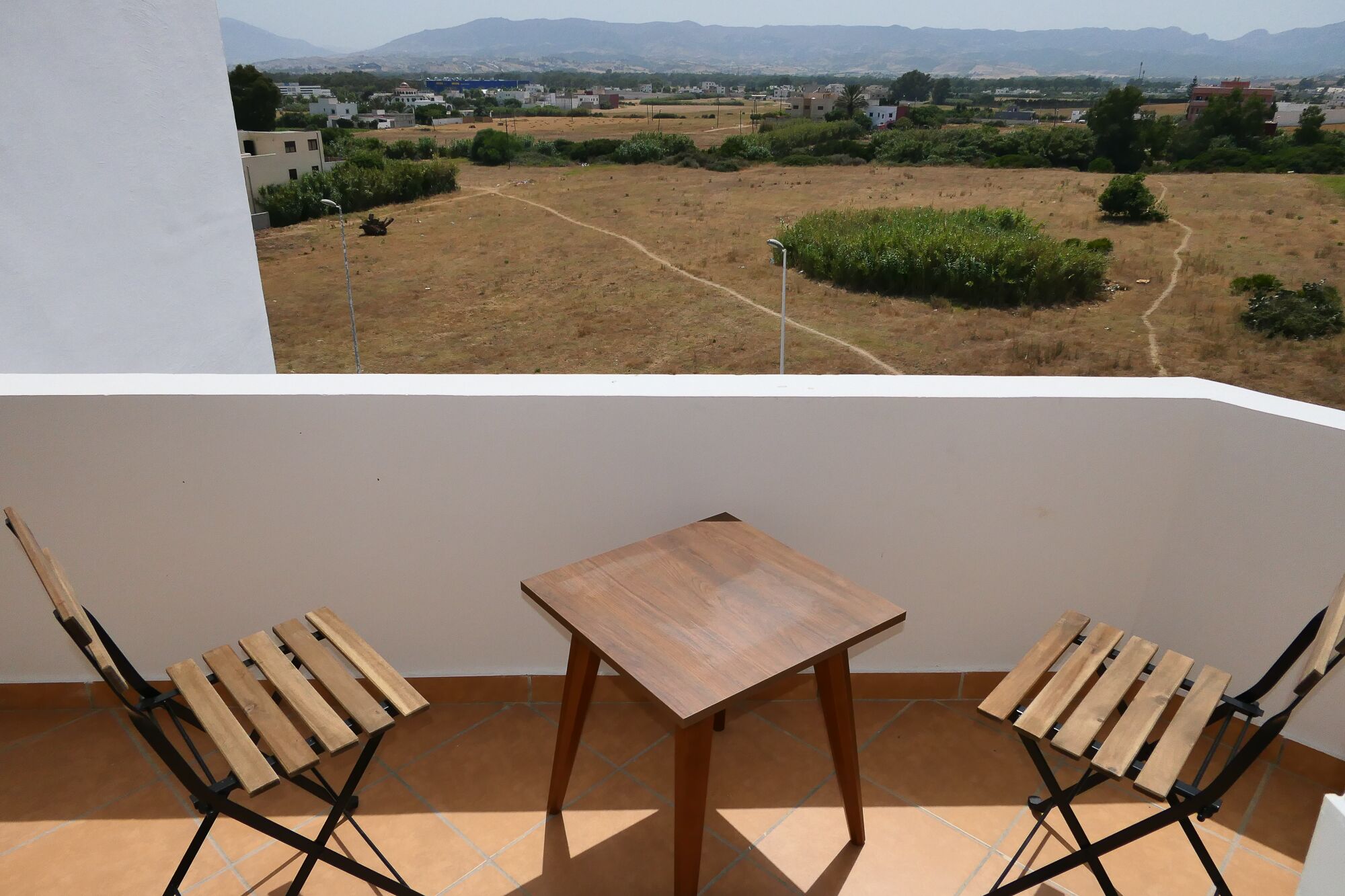 Un balcón con una mesa de madera y dos sillas de madera.