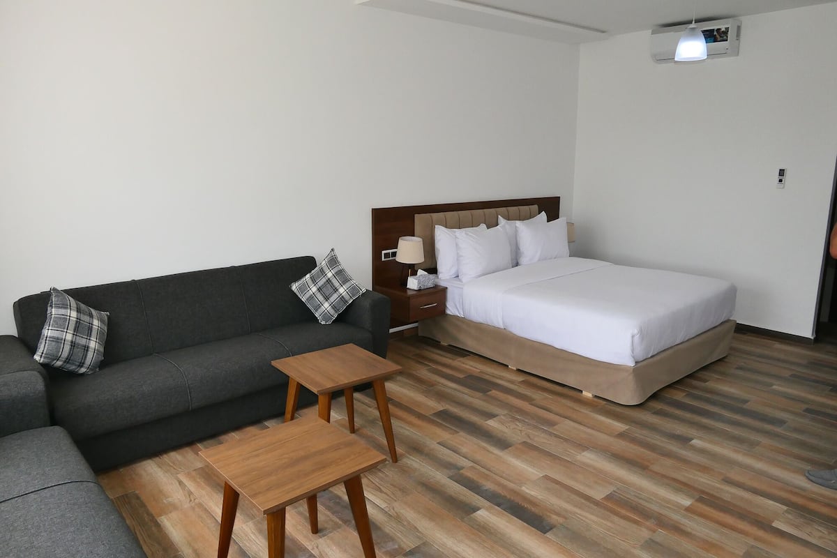 A hotel room with a bed, a sofa, a small table, and a nightstand.